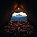 Brown double sleeping bag in tent with mountain view at dawn