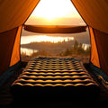 Double inflatable sleeping pad in tent with lake view at sunrise