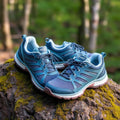 Women's outdoor hiking sneakers on a mossy rock with forest background